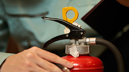 person checking safety aspect of fire extinguisher
