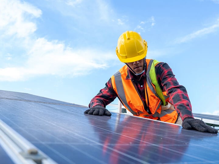 Engineer in safety harness and hard hat doing a functional safety test on a solar panel